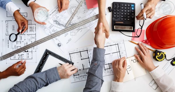 Picture of businessmen's hands on white table with documents, coffee and drafts